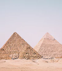 Two large pyramids stand majestically in a vast desert landscape under a clear blue sky.