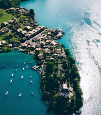 A small island surrounded by calm lake waters, featuring lush greenery and a clear blue sky above.